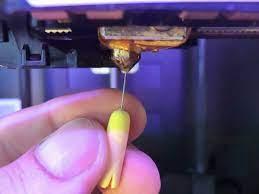 Close-up of a 3D printer printing a yellow plastic part.