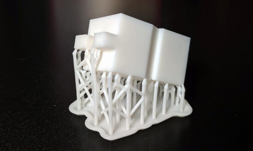 3D printed white calibration cube with tree-like supports.