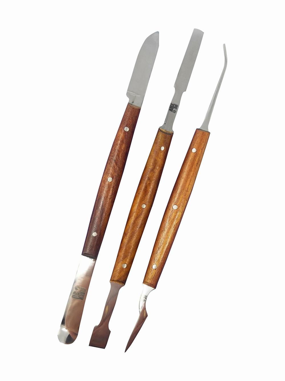 Three metal dental tools with wooden handles.