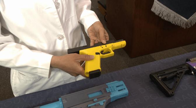 A close-up of a person holding a yellow 3D-printed handgun.