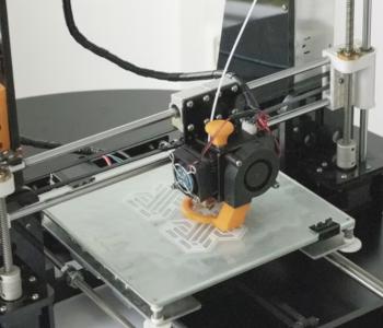 A 3D printer is printing an orange-colored object.