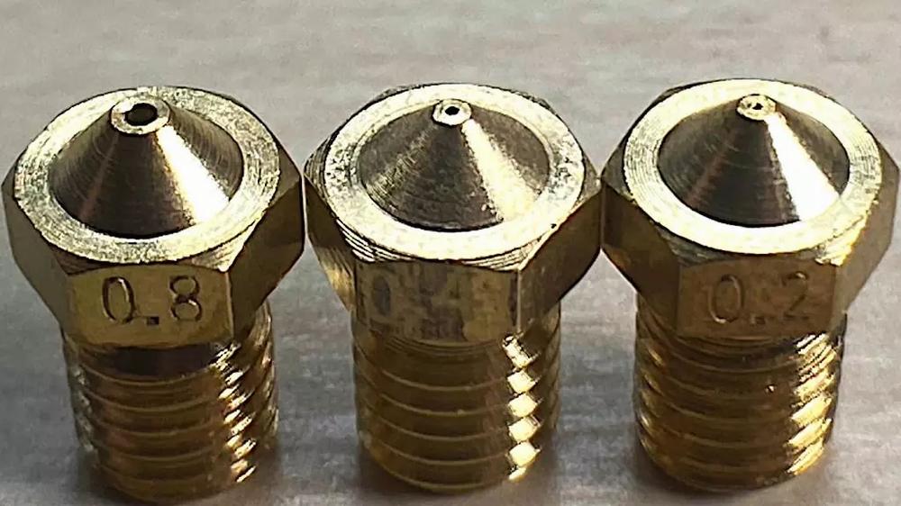 Three brass nozzles of different sizes for a 3D printer.