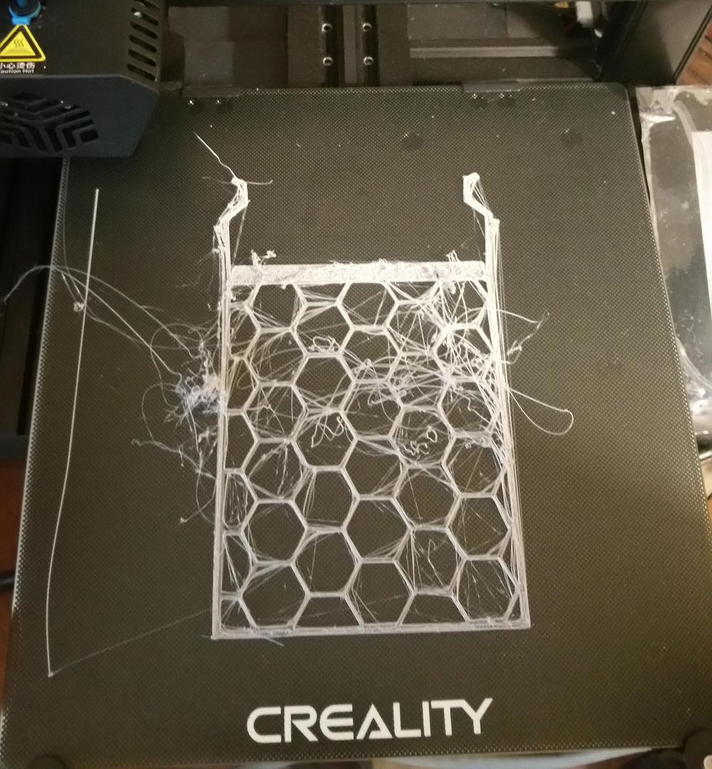 3D printed white plastic basket with a honeycomb pattern on a black print bed.