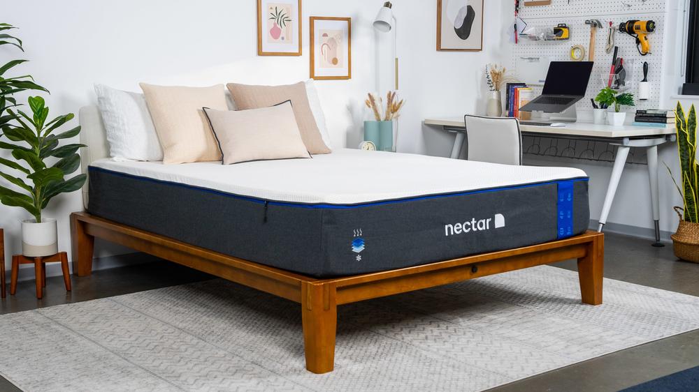 A king-sized Nectar memory foam mattress on a wooden bed frame in a bedroom with a desk and a computer.