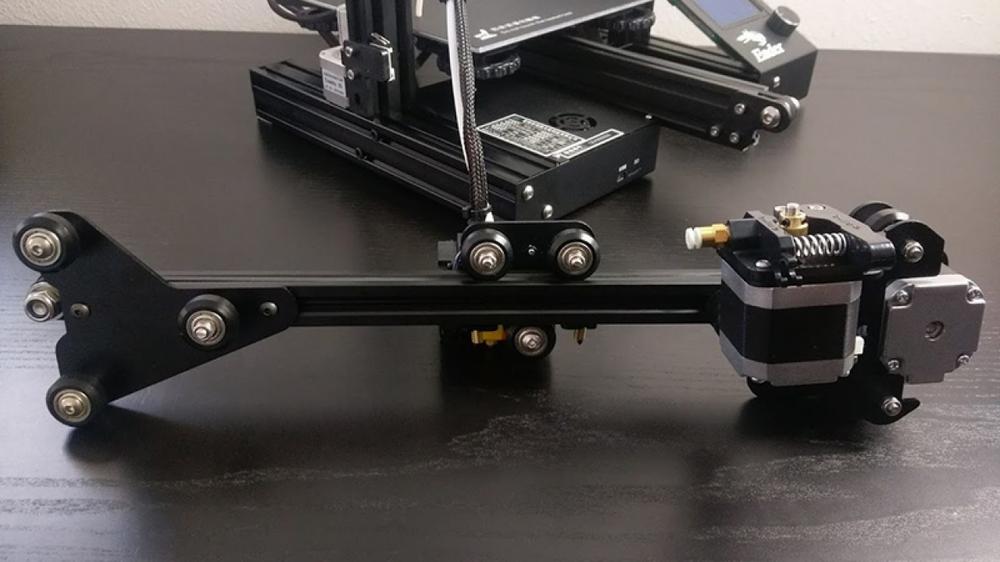 Close-up of the X-axis of a 3D printer showing the stepper motor, belts, and wheels.