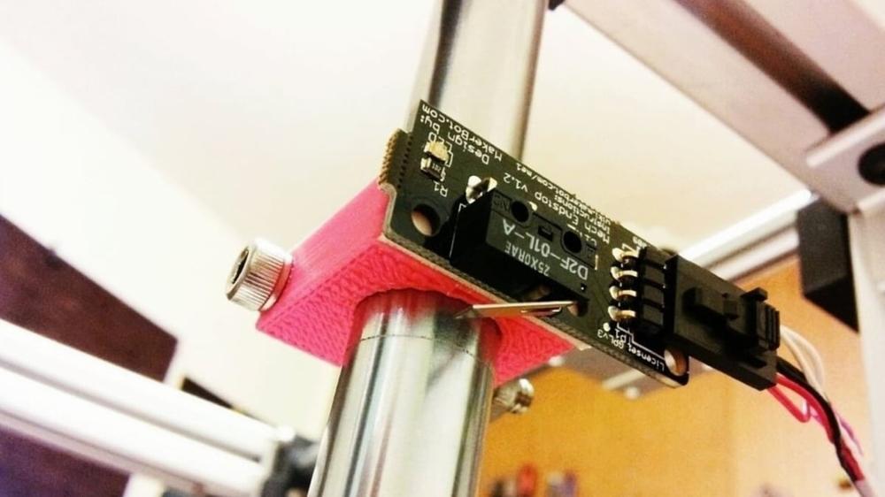 A limit switch mounted to a metal rod using a pink 3D printed bracket.