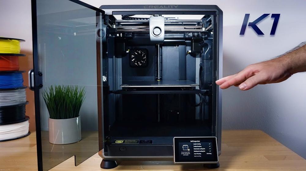 The image shows a person opening the door of a Creality 3D printer.