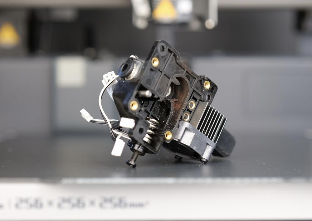 A close-up of a broken 3D printer extruder.