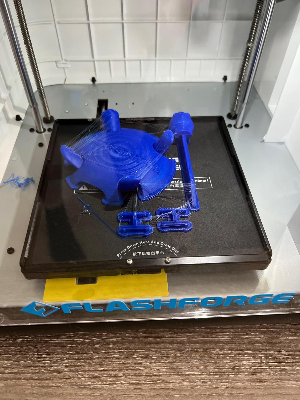 A 3D printer prints a blue object.