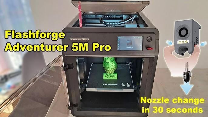 The image shows a Flashforge Adventurer 5M Pro 3D printer with a green owl figurine on the print bed and the nozzle changing.