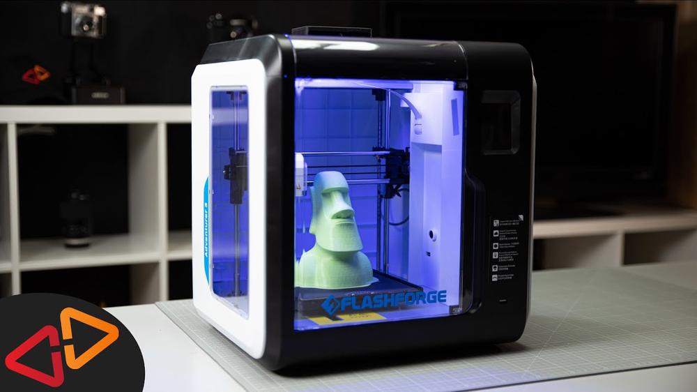 A 3D printer is printing a green figurine of a tiki head.