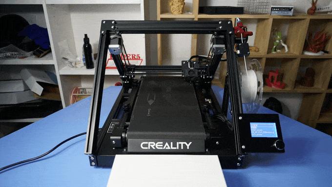 A 3D printer is printing a black object on a blue table.