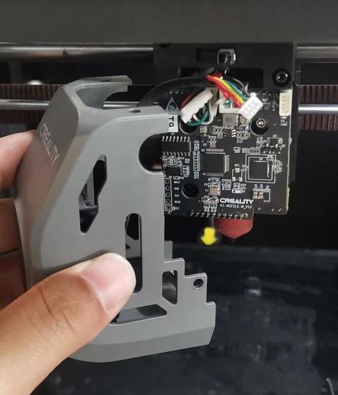 A hand holds a 3D printers control box cover.