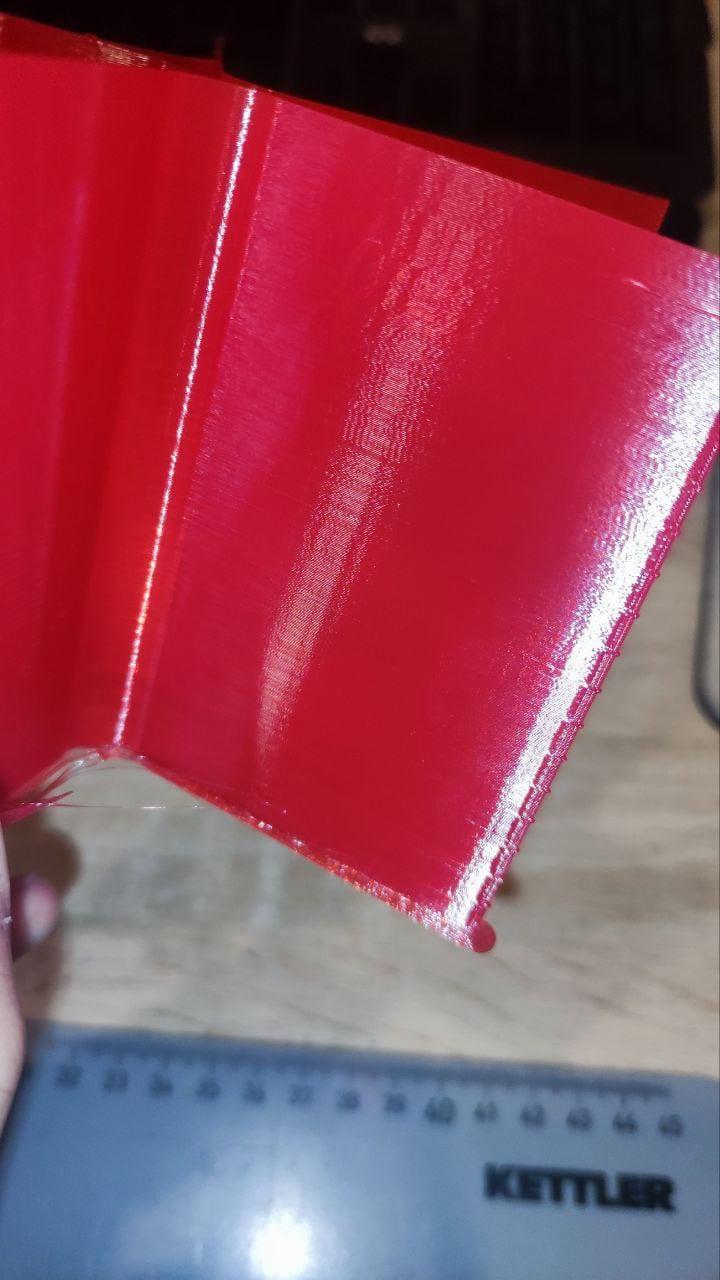 Close-up of a 3D printed object, showing the smooth surface and vibrant red color.