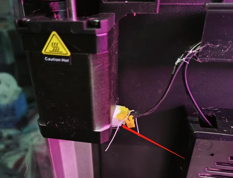 A red arrow points to a yellow electrical connector on the side of a 3D printer.