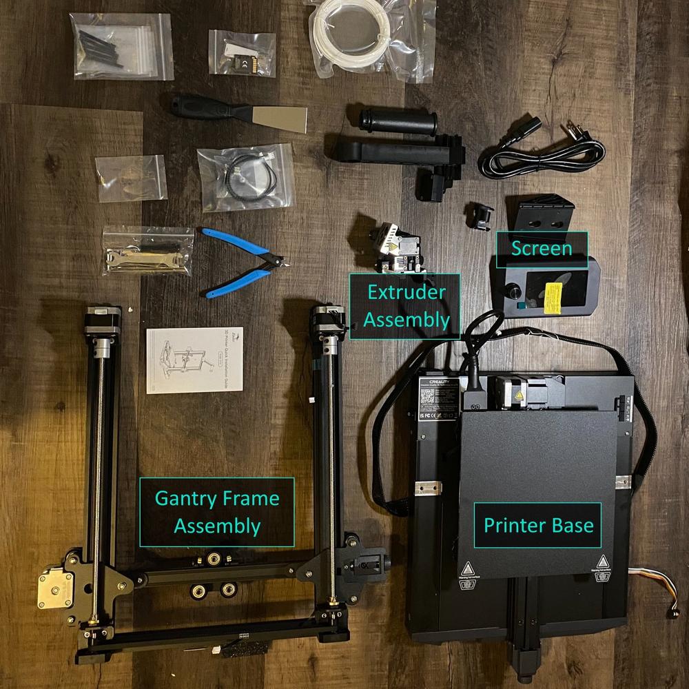 The image shows the components of a Creality Ender 3 V2 3D printer, including the printer base, gantry frame assembly, extruder assembly, screen, and various tools and accessories.