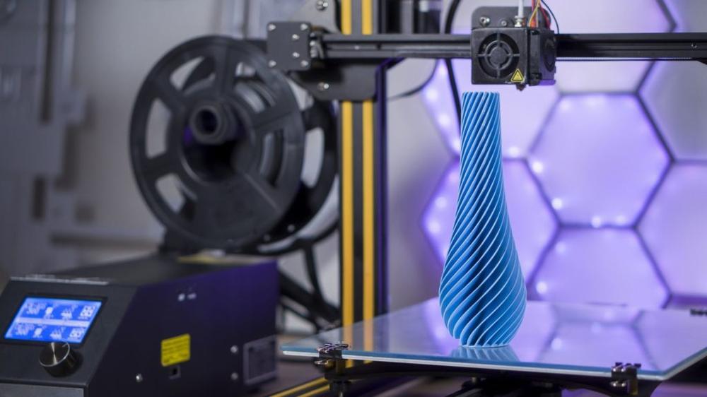 A 3D printer is printing a blue vase.