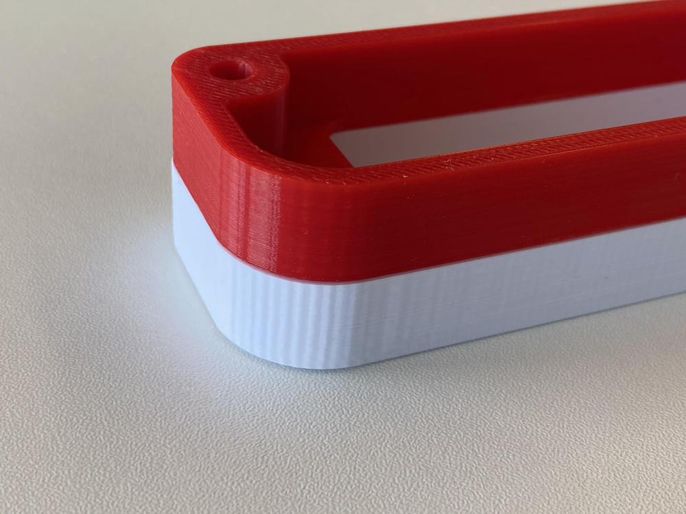 A red and white 3D printed part with a hole on one end.