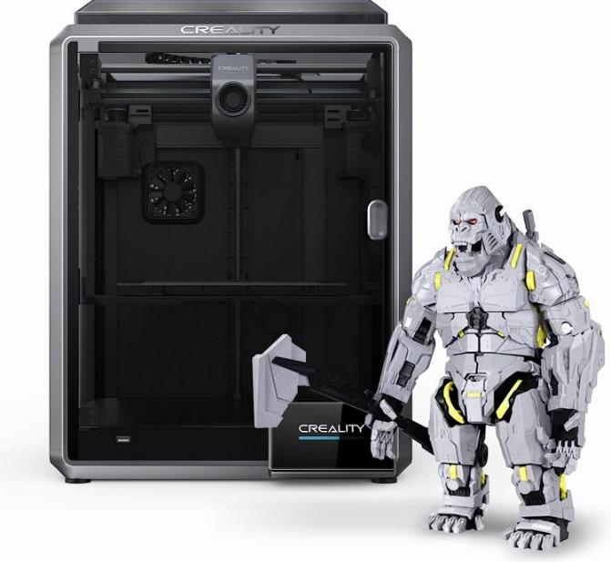 A 3D printer next to a grey action figure of a gorilla holding a hammer.