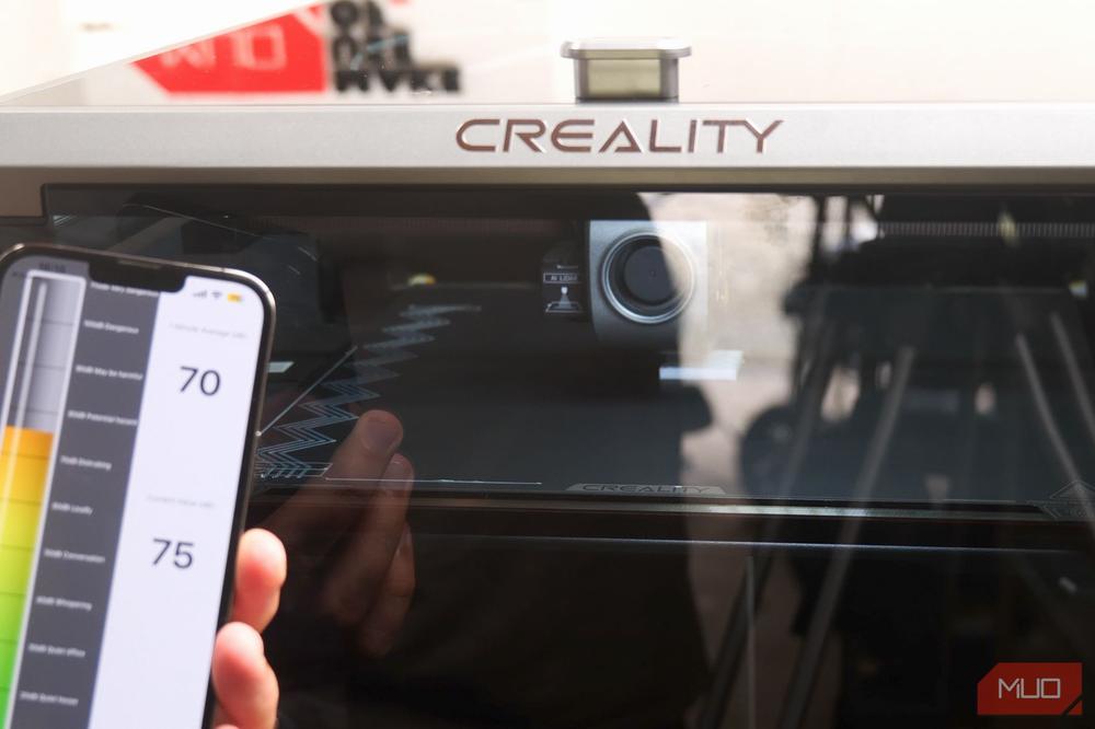 A person is using a Creality 3D printer with a touchscreen interface.