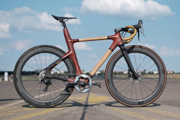 The image shows a racing bicycle made of carbon fiber with a wooden frame.