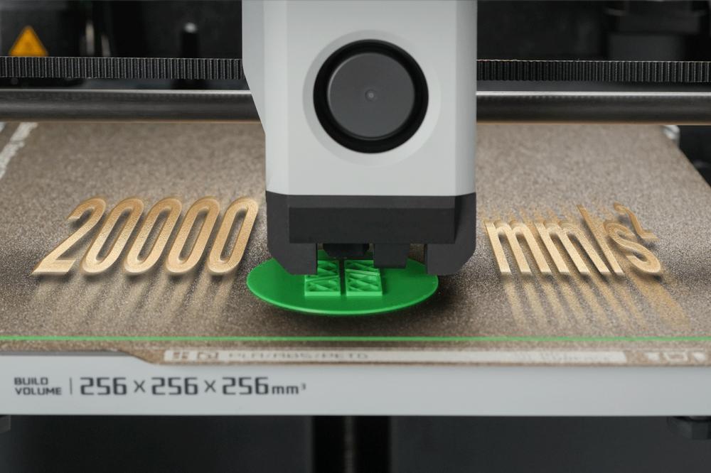 A 3D printer is printing a green object on a brown surface with text that reads 20000 marks.