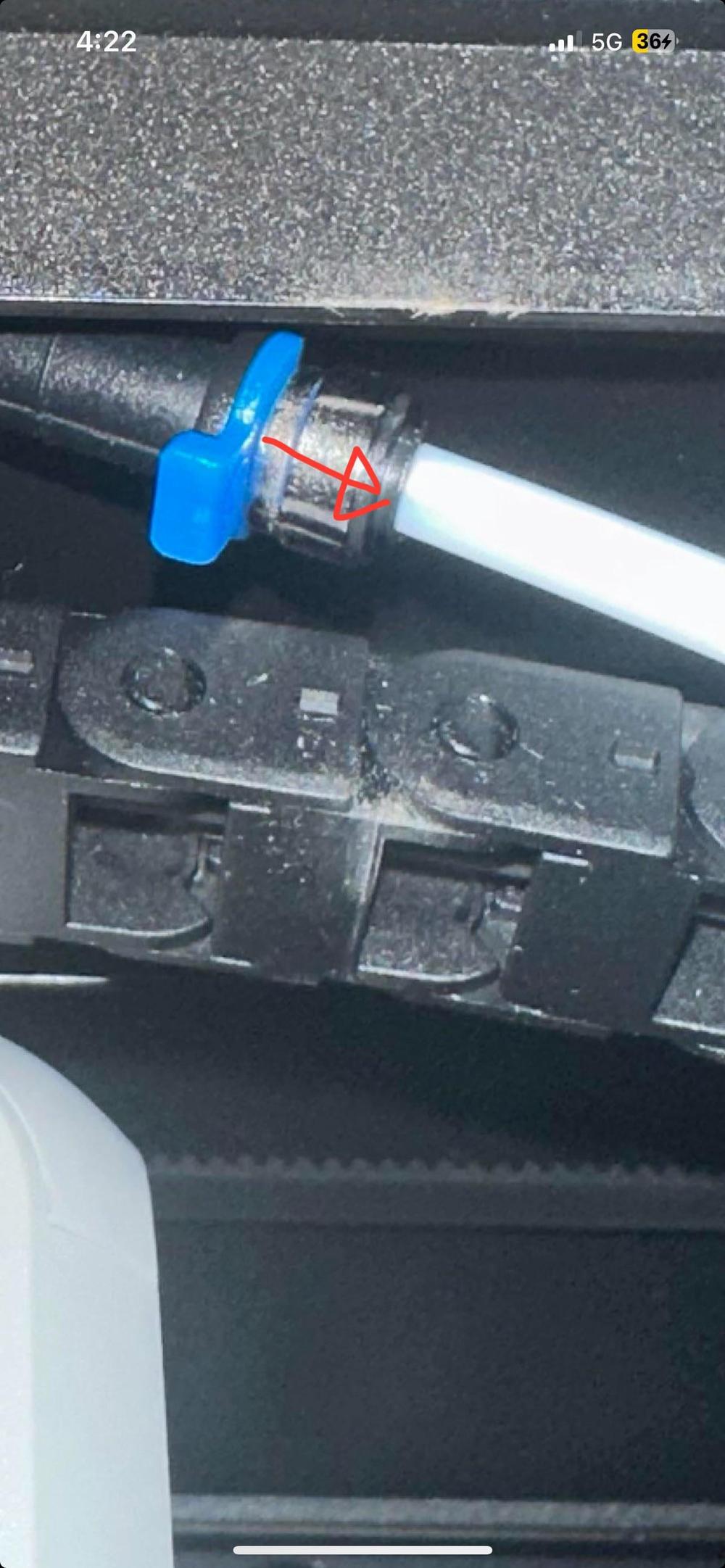 A red arrow points to a small blue plastic part that is attached to a white tube.