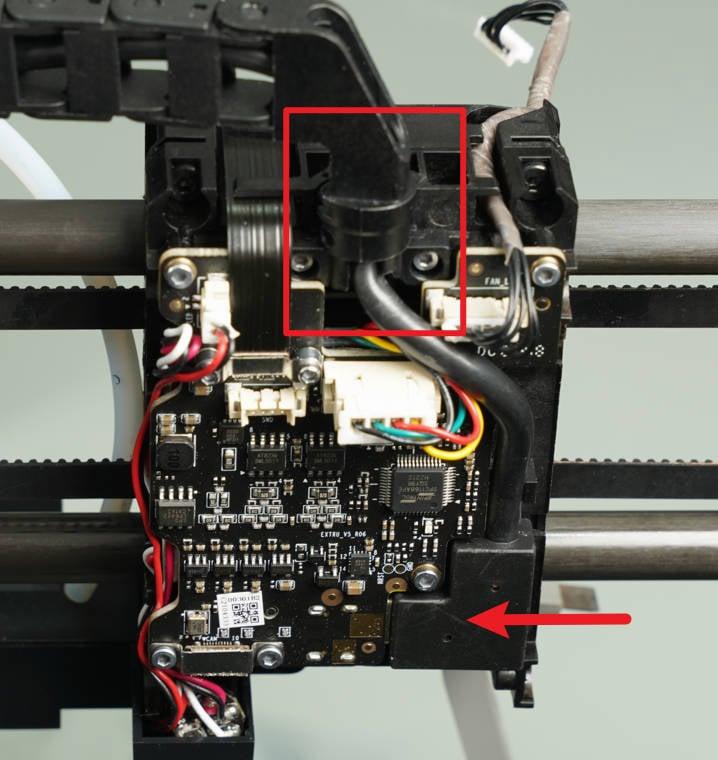 The red arrow is pointing to the black extruder knob on the right side of the printer.