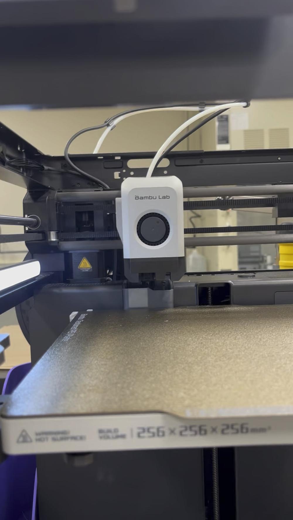 A close-up of a 3D printers hot end and build surface.