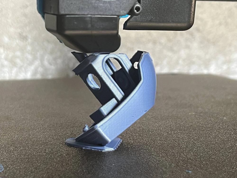 A 3D printer is printing a blue plastic part.