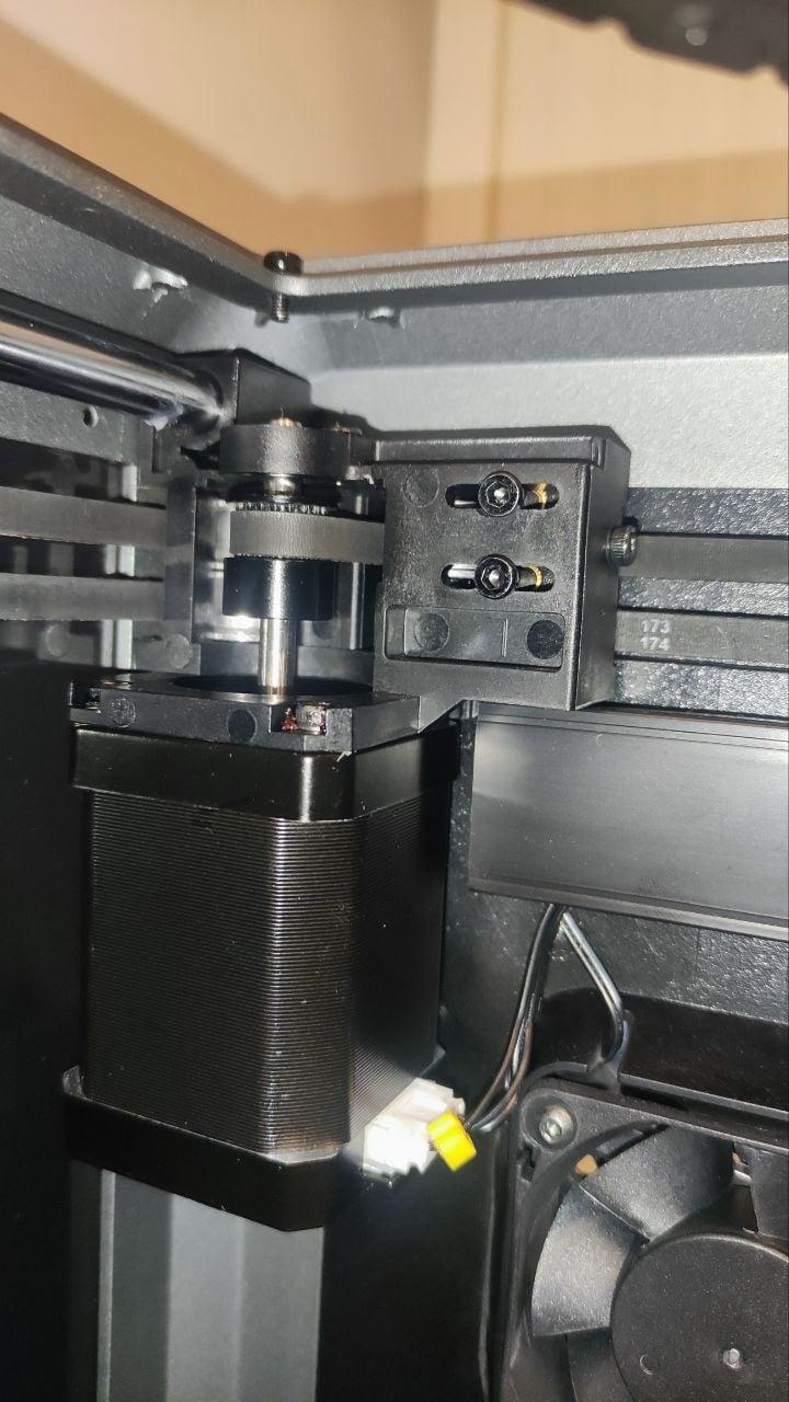 A close-up of a 3D printers extruder motor and filament tensioner.