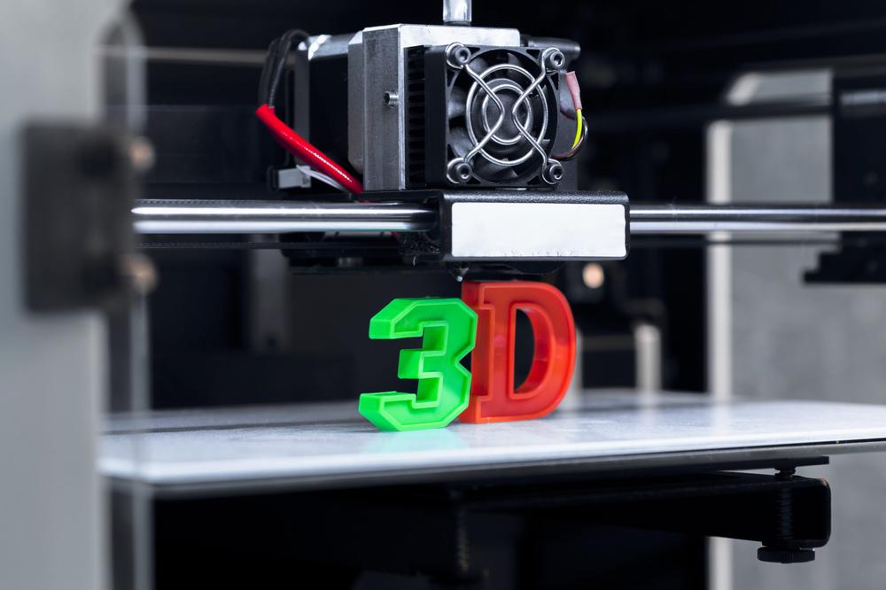 A 3D printer prints a green and red 3D model of the letters forming 3D.