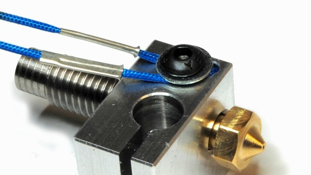 A blue Bowden tube is being fed into a silver metal extruder.