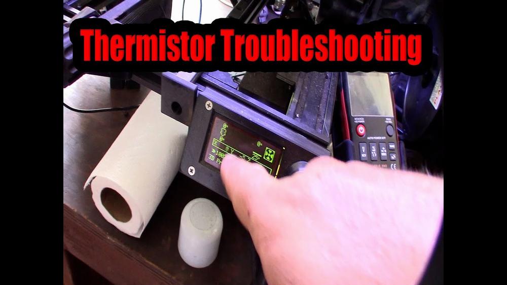 A person is shown using a multimeter to troubleshoot a thermistor while 3D printing.