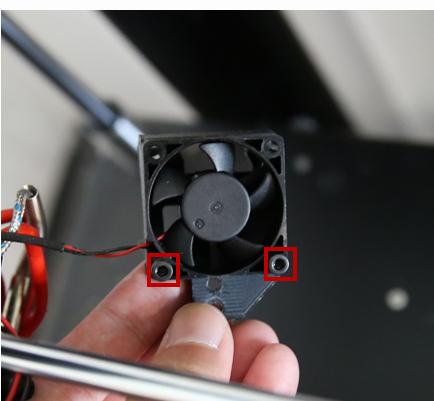 Two red circles highlight the two screws that need to be removed to detach the cooling fan from the heatsink.