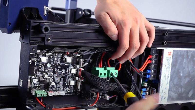 A technician is installing a circuit board into a 3D printer.