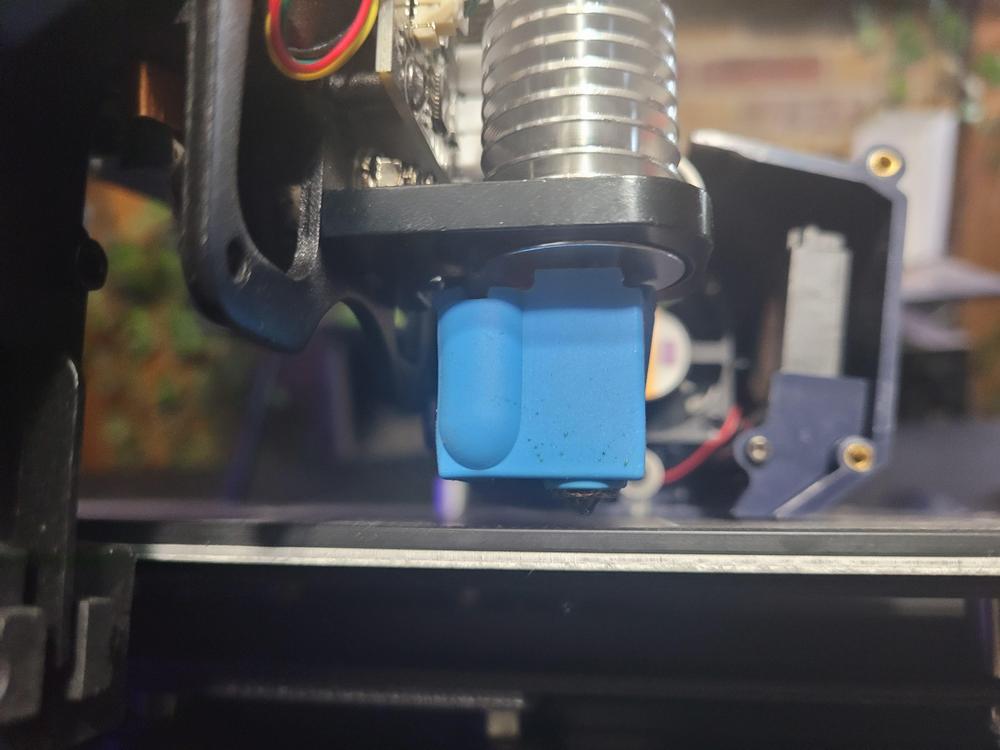 Close-up of a blue silicone sock covering the hot end of a 3D printer.
