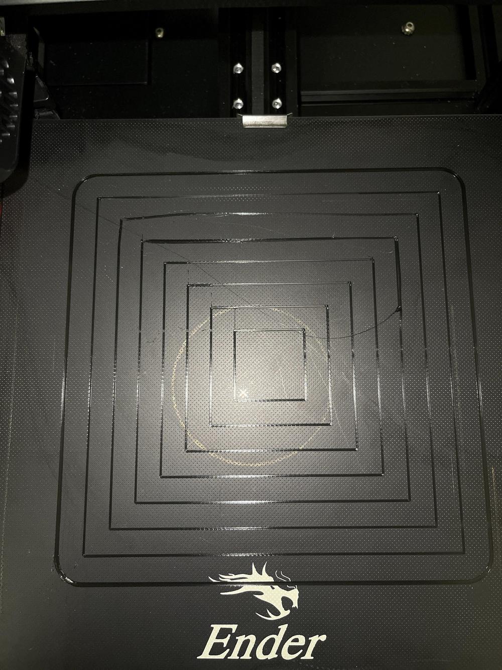 Close-up of a 3D printers print bed with a circular pattern of filament.