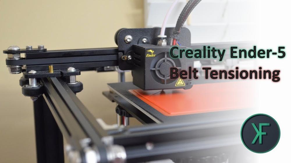 A 3D printer with a red print bed and a black frame is shown with a close-up of the belts and gears.