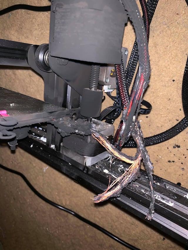 A 3D printer with melted plastic on the nozzle and wires.