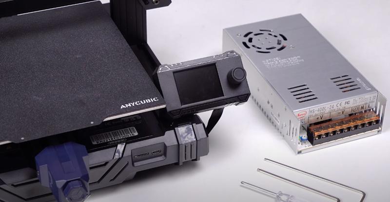 The image shows an Anycubic 3D printer with a power supply and some tools.