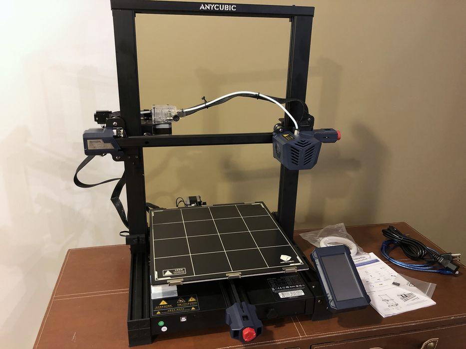 The image shows an Anycubic Mega X 3D printer with a black frame and a blue build plate.