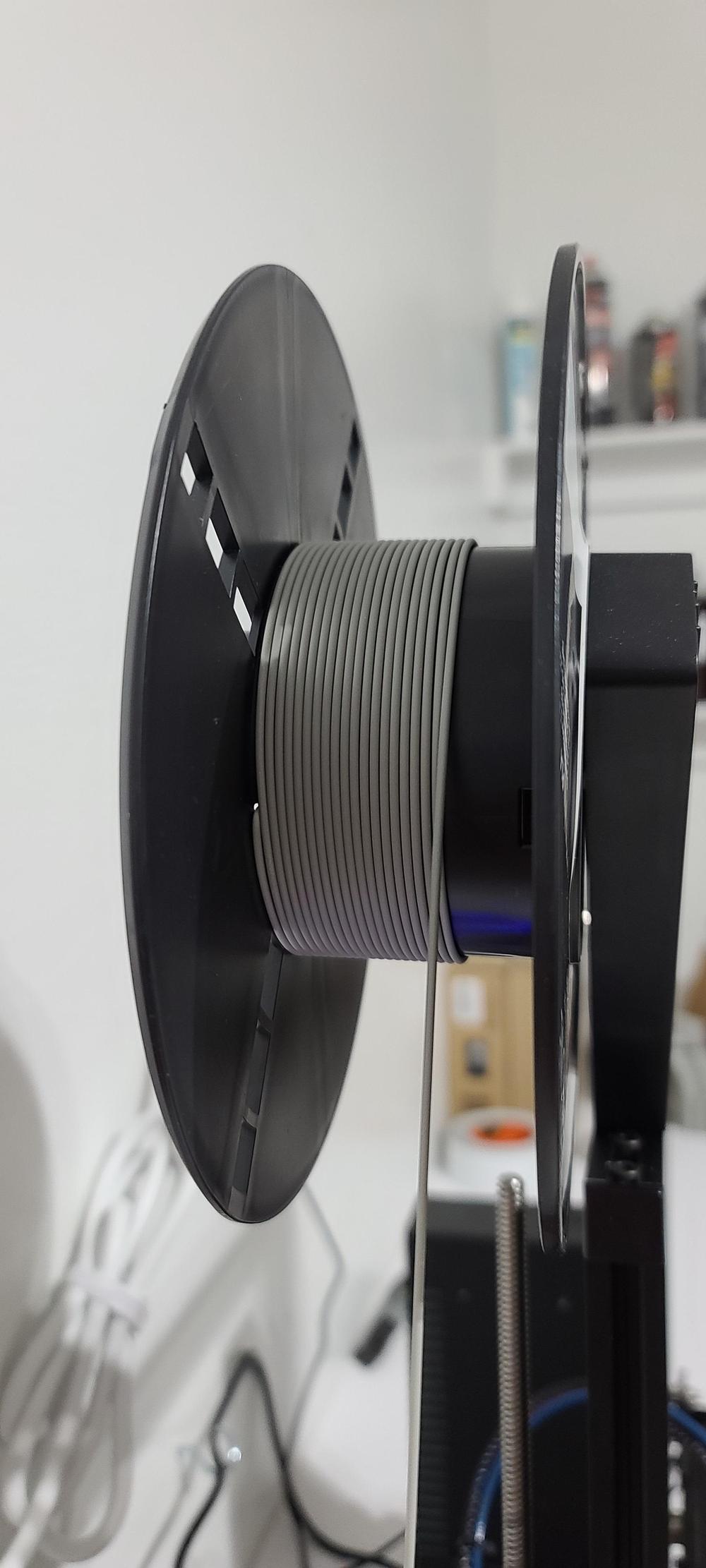 A spool of gray filament on a 3D printer.