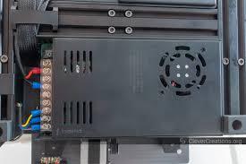 The image shows a black power supply unit with a large fan mounted on the bottom.