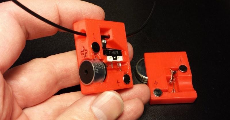 A hand holding a small red 3D printed box with a slide switch and a battery.